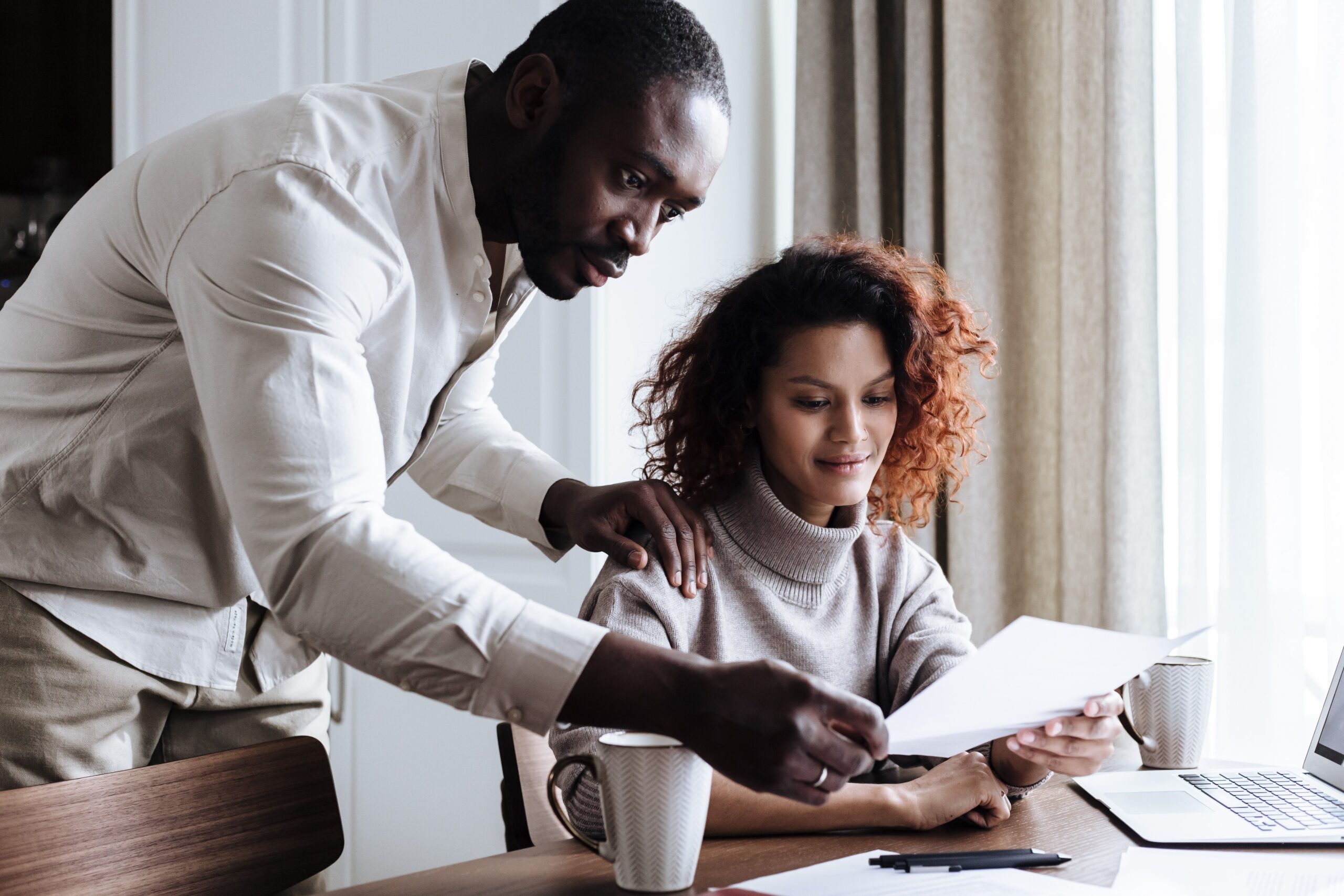 A couple reviewing property documents together with a laptop at home